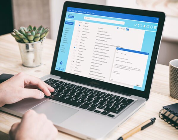 Email message communication. Man working with a computer, client mail list on laptop screen, office desk background.