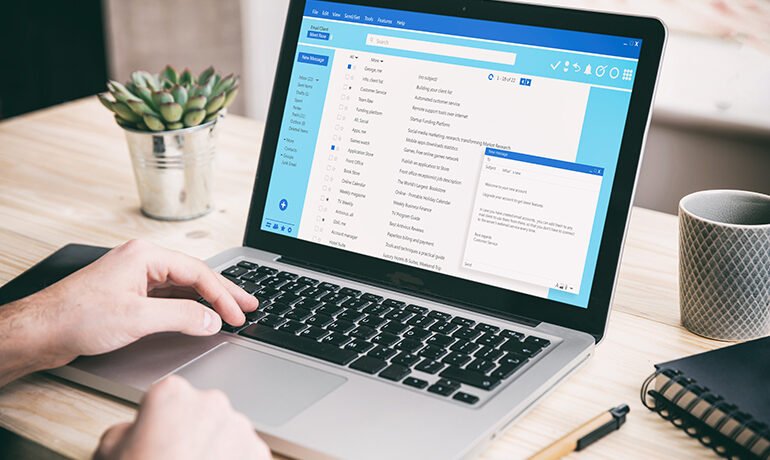 Email message communication. Man working with a computer, client mail list on laptop screen, office desk background.